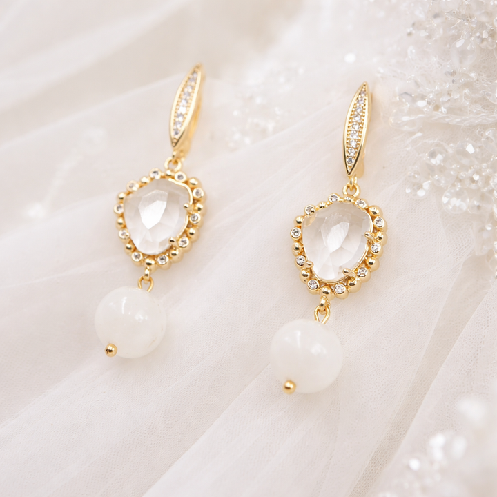 apzeltīti angļu aizdares auskari ar neregulāras formas kristālbaltu kristālu, kuram piestiprināta 10mm mēnessakmens bumbiņa