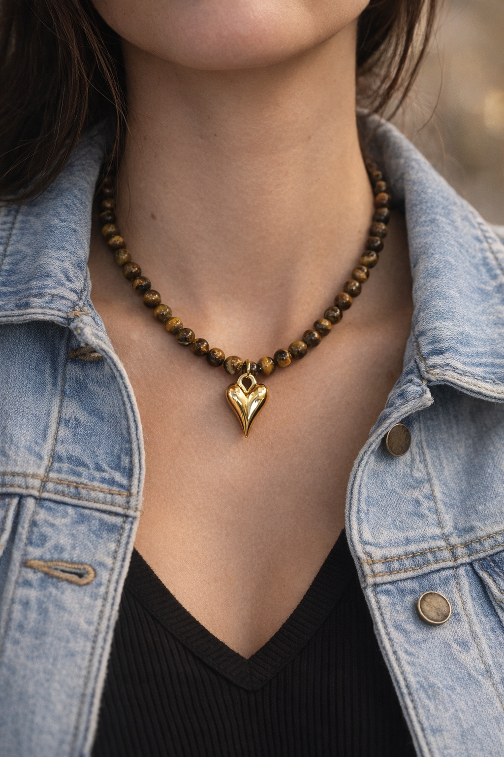 Eleganta brūna tīģeracs kaklarota ar zelta sirds kulonu sievietei uz kakla.