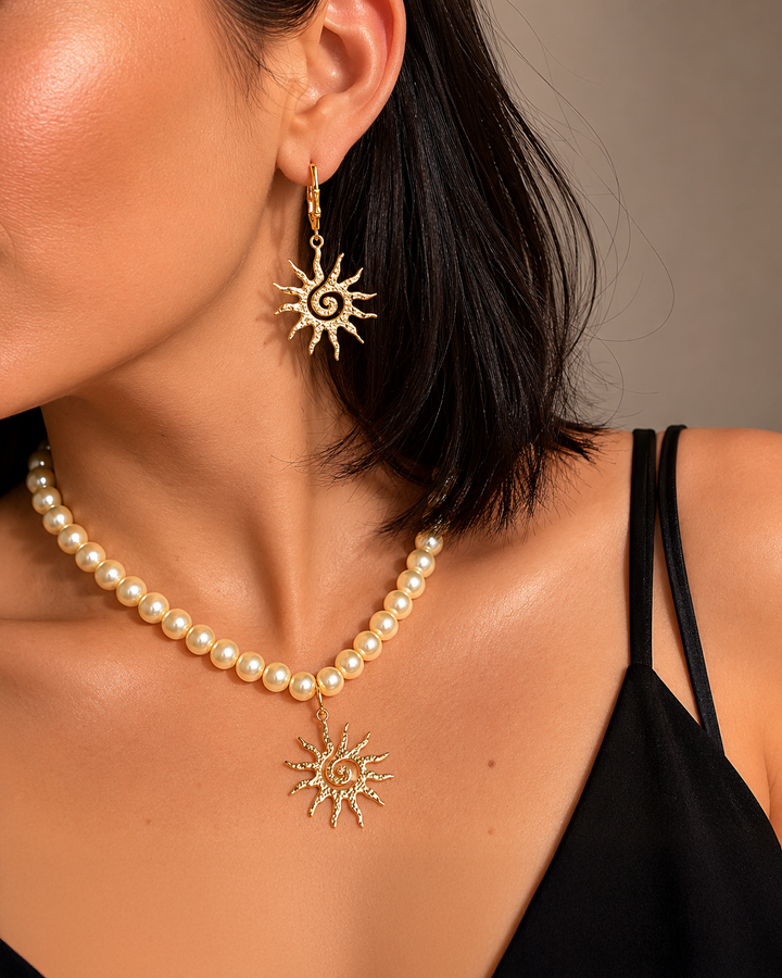 Eleganta pērļu kaklarota ar saules kulonu un akcentējoši saules formas auskari luxury jewelry aesthetic stilā. Rotas veidotas siltā zelta tonī un papildinātas ar pērļu pērlītēm, radot izsmalcinātu un sievišķīgu tēlu. Ideāli piemērotas vakara outfitiem, fashion editorial fotosesijām un romantiskam soft glam stilam.